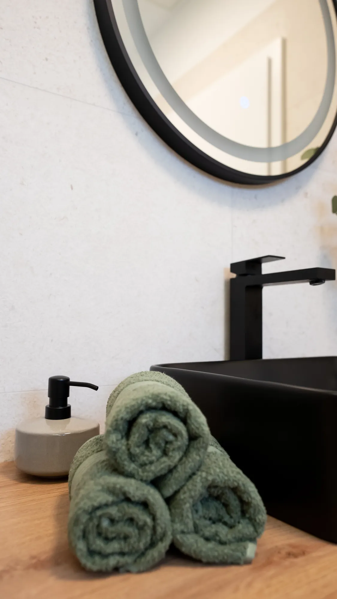 Detaliu de baie: prosoape verde eucalipt, lavoar negru